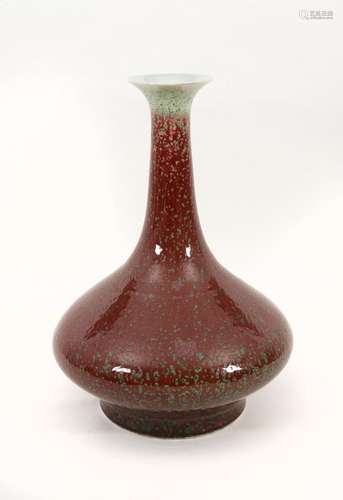 A porcelain vase with a red and green glaze and a flat belly...