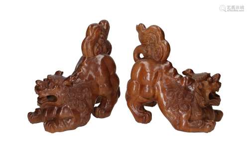 A pair of carved wooden sculptures depicting Foo dogs with g...