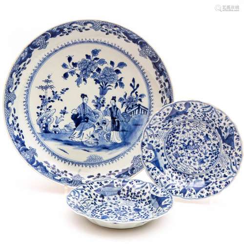 A blue and white charger with figures and two smaller plates