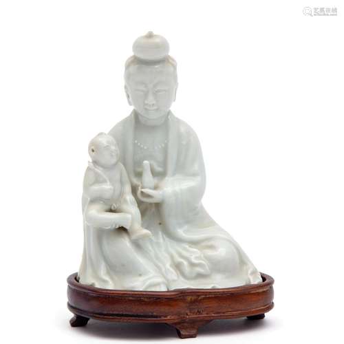 A Blanc de Chine seated Guanyin with child on wooden base