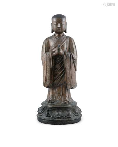 A HEAVY CASTED BRONZE FIGURE OF A STANDING ATTENDANT OR MONK...