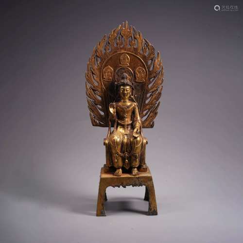 A gilt bronze statue of buddha with flaming halo
