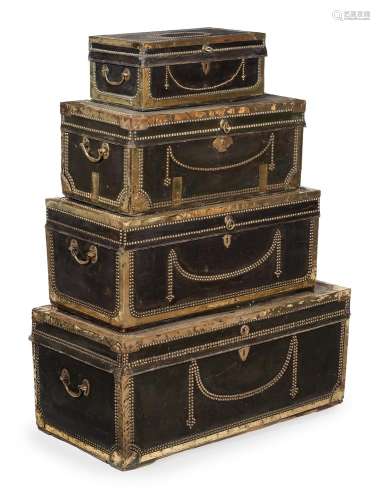 A GRADUATED SET OF FOUR LEATHER AND BRASS BOUND TRUNKS, FIRS...