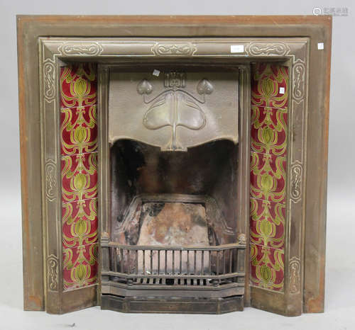 An Edwardian Art Nouveau cast iron fireplace, inset with gre...