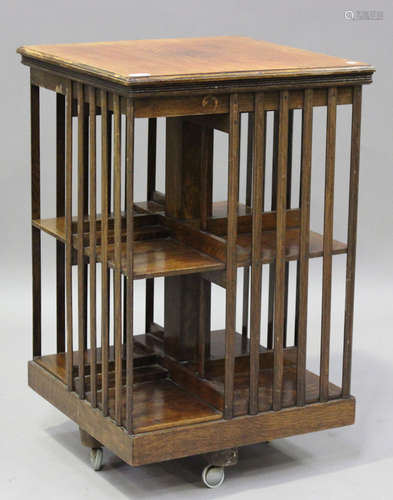 An Edwardian oak revolving bookcase with hinged lid and slat...