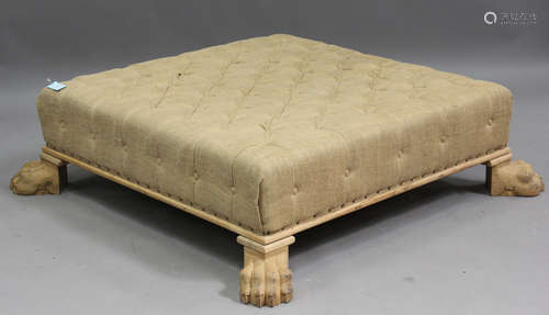 A large modern footstool, covered in buttoned hessian, on ca...