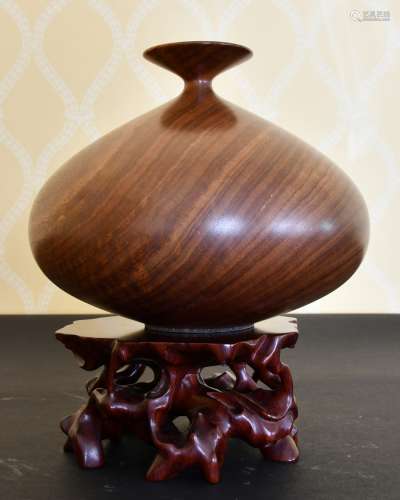 A GOOD HEAVY CARVED WOOD VASE on a stand.