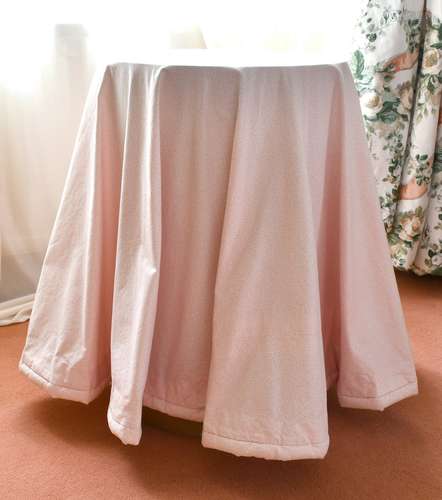 A SMALL CIRCULAR TABLE with fabric cover. 1ft 5ins diameter.