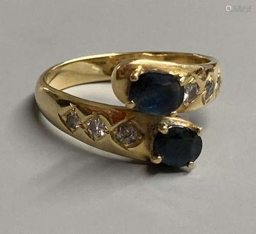 A modern 18ct and two stone sapphire crossover ring, with di...