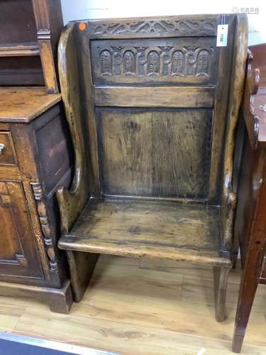 An 18th century style narrow oak panelled wing back settle, ...