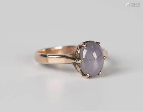 A gold ring, claw set with an oval cabochon star sapphire, w...