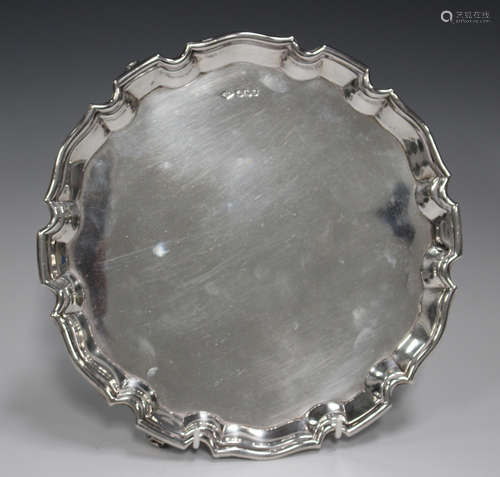 A George V silver circular salver with piecrust rim, on volu...