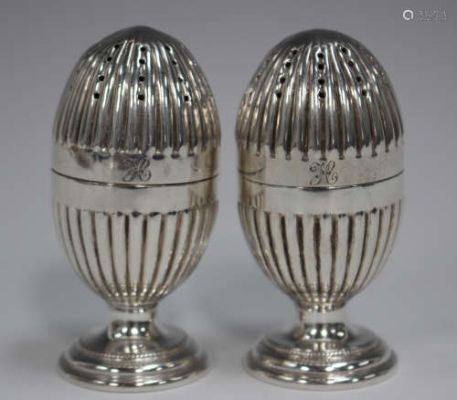 A pair of late Victorian silver pepper casters, each of reed...