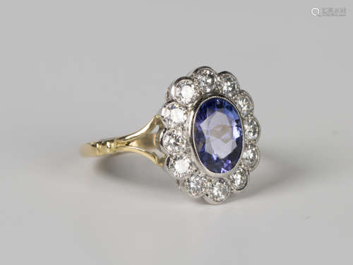 A tanzanite and diamond cluster ring, collet set with the ov...