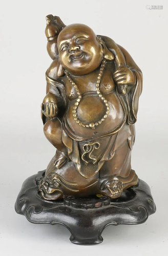 Old Chinese bronze laughing Buddha on a wooden