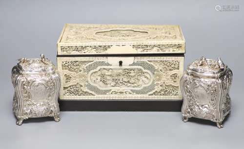 A good pair of George II embossed silver tea caddies and cov...