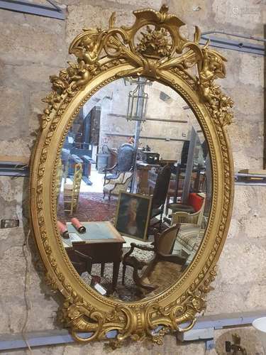 Miroir ovale, cadre en bois et stuc doré à décor d'angelots,...