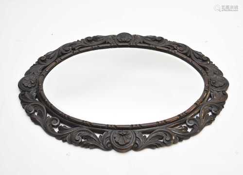 A carved oak oval wall mirror