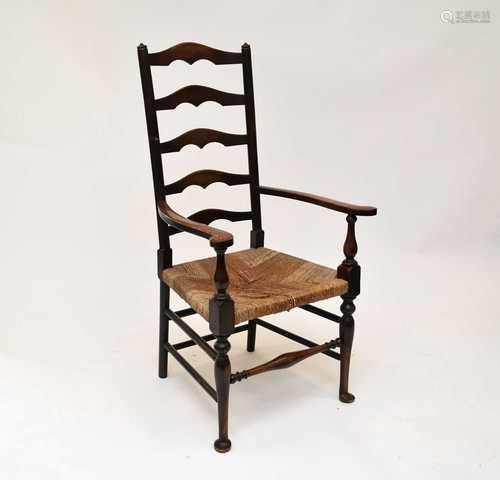 An oak ladder back rush seated open armchair