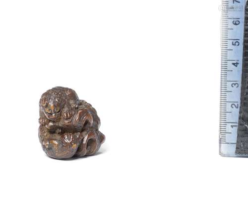 A wood netsuke of a shishi (Chinese mythological lion dog) a...