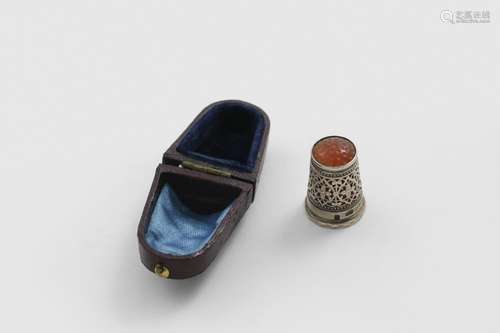 AN EDWARDIAN THIMBLE with pierced sides and a hardstone top,...