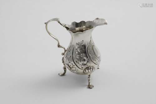 A GEORGE II SMALL BALUSTER CREAM JUG on three legs with a sh...