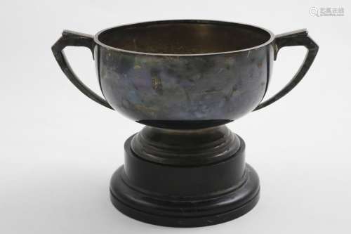 AN ELIZABETH II ART DECO REVIVAL TWO-HANDLED CUP on an eboni...