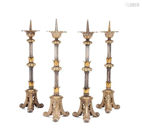 A SET OF FOUR GOTHIC REVIVAL SILVERED AND GILT METAL CANDLES...
