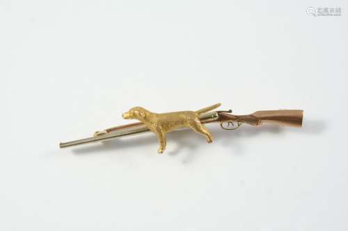 A TWO COLOUR GOLD SHOOTING BROOCH depicting a shotgun and a ...