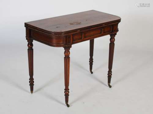 An early 19th century rosewood games table, the hinged top o...
