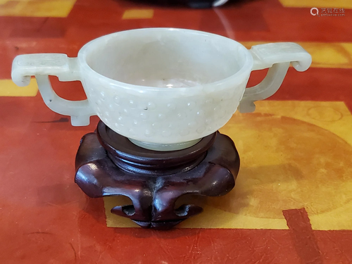 Chinese carved jade cup on wood stand.