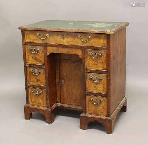 A GEORGE II WALNUT KNEEHOLE DESK, the leather top above one ...