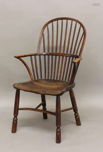 A YEW AND ELM WINDSOR CHAIR, the comb back above solid seat,...