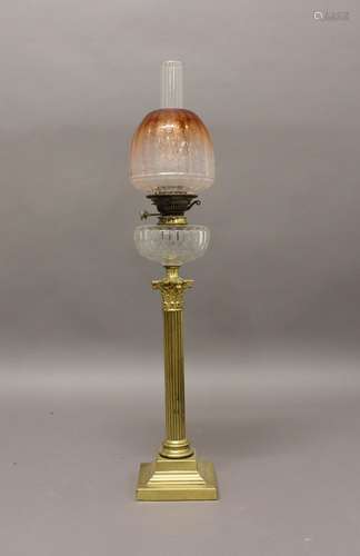 A VICTORIAN OIL LAMP AND SHADE. A Victorian oil lamp on a br...