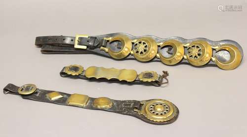 THREE LEATHER HARNESS STRAPS WITH DECORATIVE BRASSES. A poli...