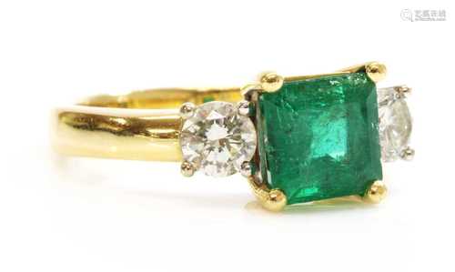 An 18ct two colour gold three stone emerald and diamond ring...