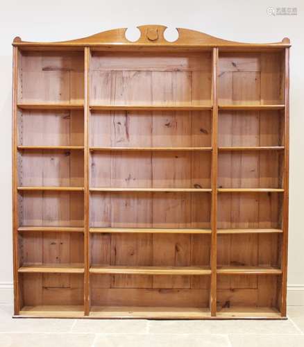 An early 20th century honey oak open bookcase, the shaped pe...