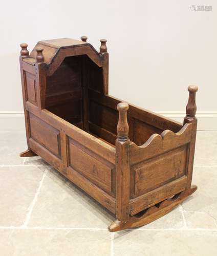 An early 19th century oak cradle, with turned finials upon a...