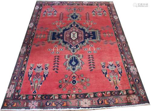 A Persian wool rug, worked with a central blue medallion