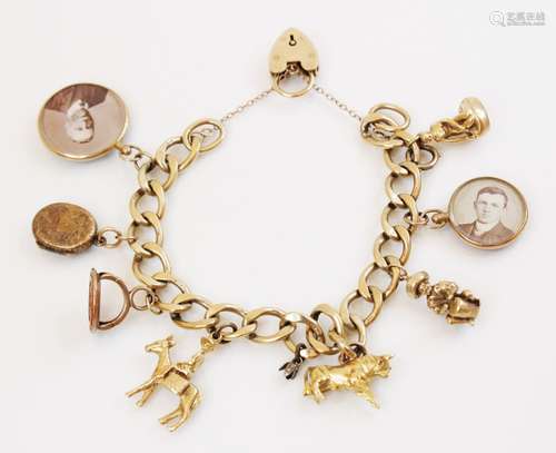 A 9ct gold curb-link charm bracelet with a heart-shaped padl...