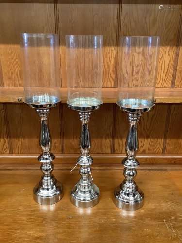 Set of three nickel plated candle stands with glass shades, ...