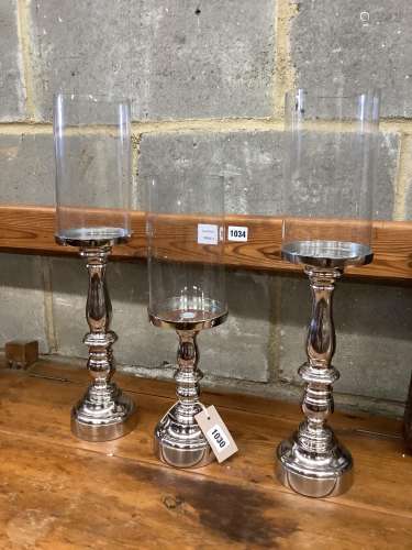 Set of three nickel plated candle stands with glass shades, ...