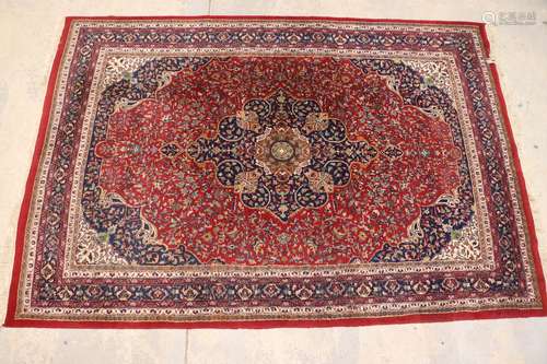 Tapis indien en laine à décor floral sur fond bleu et rouge....