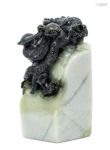 A black and white jade seal, the top carved with a dragon cl...