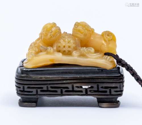 A loquat Tianhaung carving of two lions and a brocade ball, ...