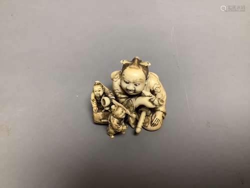 A Japanese ivory netsuke of two miniature men carrying a Sam...