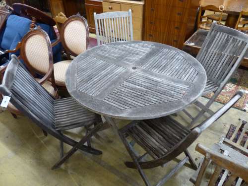 A teak garden table, 125cm diameter and four matching chairs...