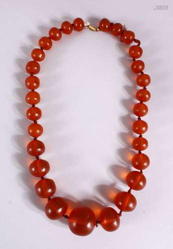 A 19TH CENTURY CHINESE CARVED AMBER BEAD NECKLACE, comprisin...