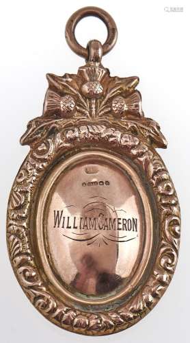An oval 9ct gold prize watch fob shield, surmounted by thist...