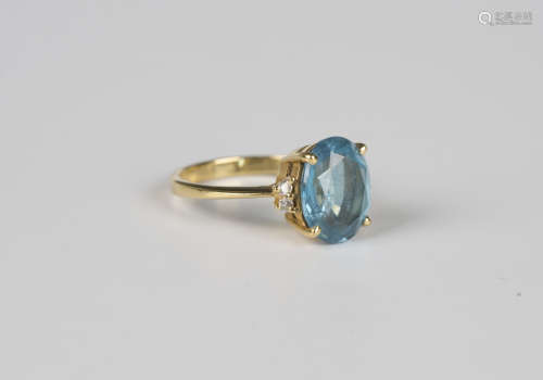 A gold ring, claw set with an oval cut blue topaz between ci...
